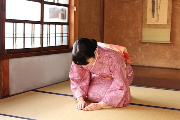 Lady in Kimono bowing on tatami room.