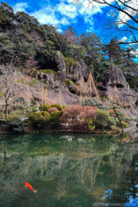 a mountain with stone caves in back of a pond